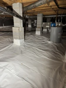 A finished crawlspace encapsulation project in Chapel Hill featuring a white vapor barrier covering the floor, sealed around concrete support pillars, with HVAC ducts and a water heater visible in the background.
