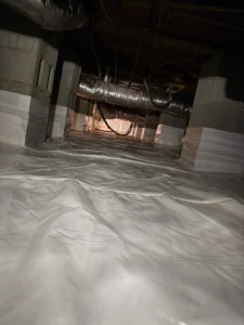 Crawl space encapsulation with a vapor barrier covering the ground and foundation piers.